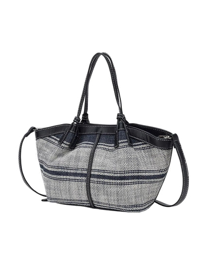 A small tote bag with a black and white herringbone patterned body, black leather trim, double top handles, and a detachable shoulder strap, shown against a plain light gray background.