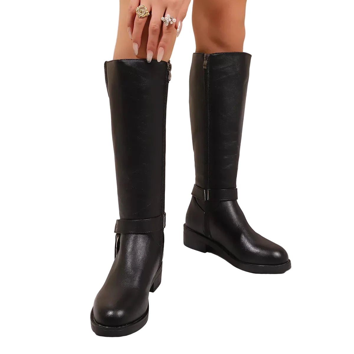 A pair of knee-high black faux-leather boots with side zippers and ankle straps, shown on a model's feet against a beige wall and white marble floor.