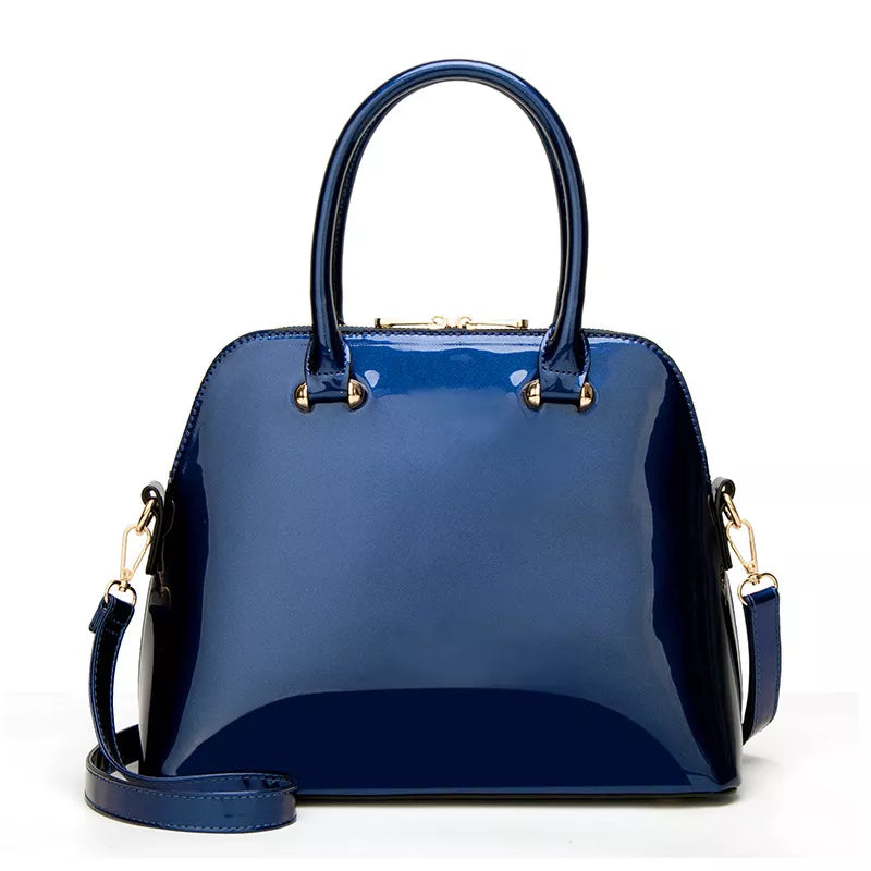 A glossy navy blue patent leather handbag with double top handles and a detachable shoulder strap, shown against a plain white background.