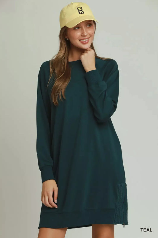 Woman wearing a teal dress and yellow cap on a plain background