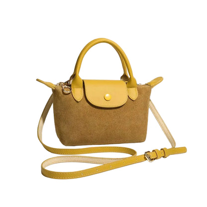 A structured mustard yellow handbag with a suede-like brown body, yellow leather handles and strap, and gold-tone hardware, photographed on a light gray studio background.
