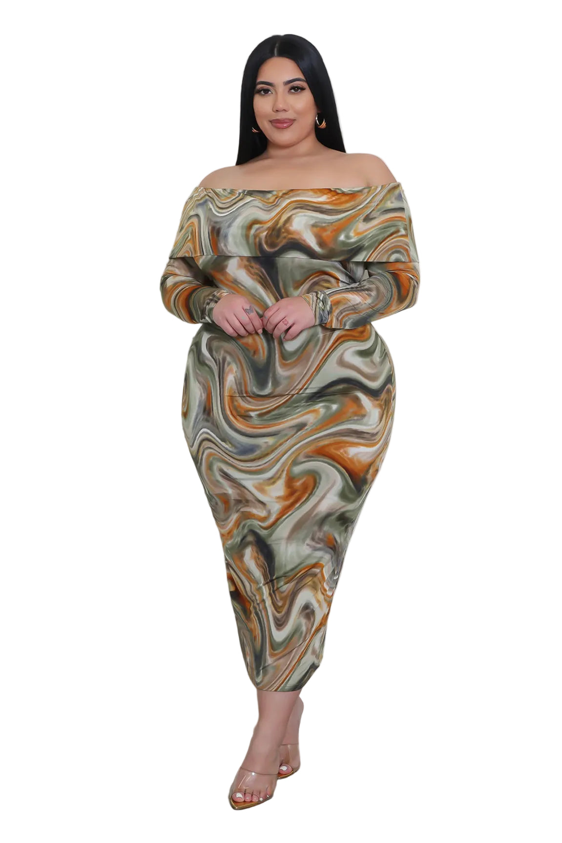 Woman wearing a patterned dress standing in a room with a white wall and small table.