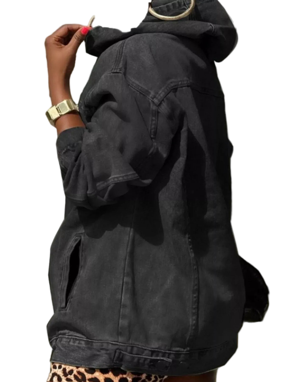 A person wearing an oversized faded black denim hooded jacket, shown from the side and back. The jacket has a washed, dark gray-black finish and is styled with a leopard-print bottom and gold accessories.