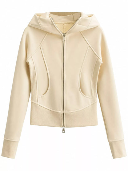 A cropped zip-up hoodie in a light cream or off-white color, featuring diagonal seam details, a front zipper, and a hood, shown against a plain white background.
