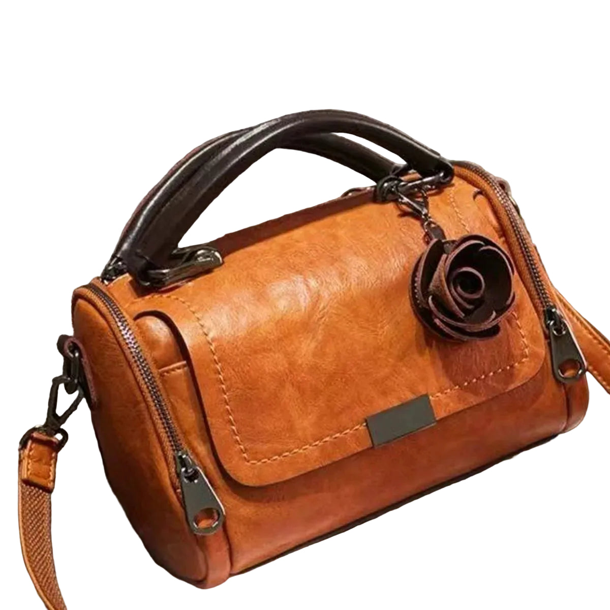 A brown faux-leather handbag with a top handle, zippered closure, and a dark brown rose charm, resting on a gray textured sofa.