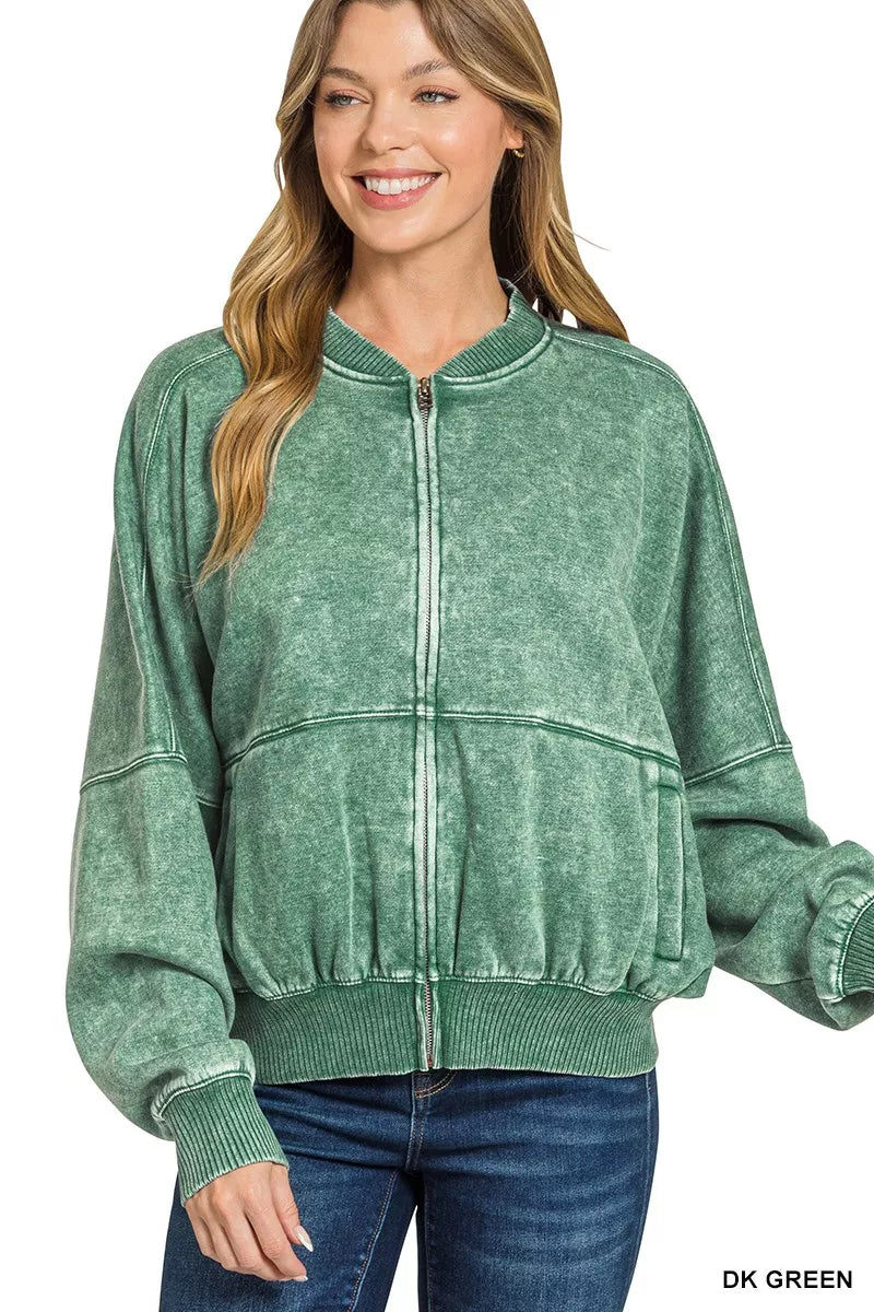 Woman wearing a green zip-up sweatshirt with a plain background