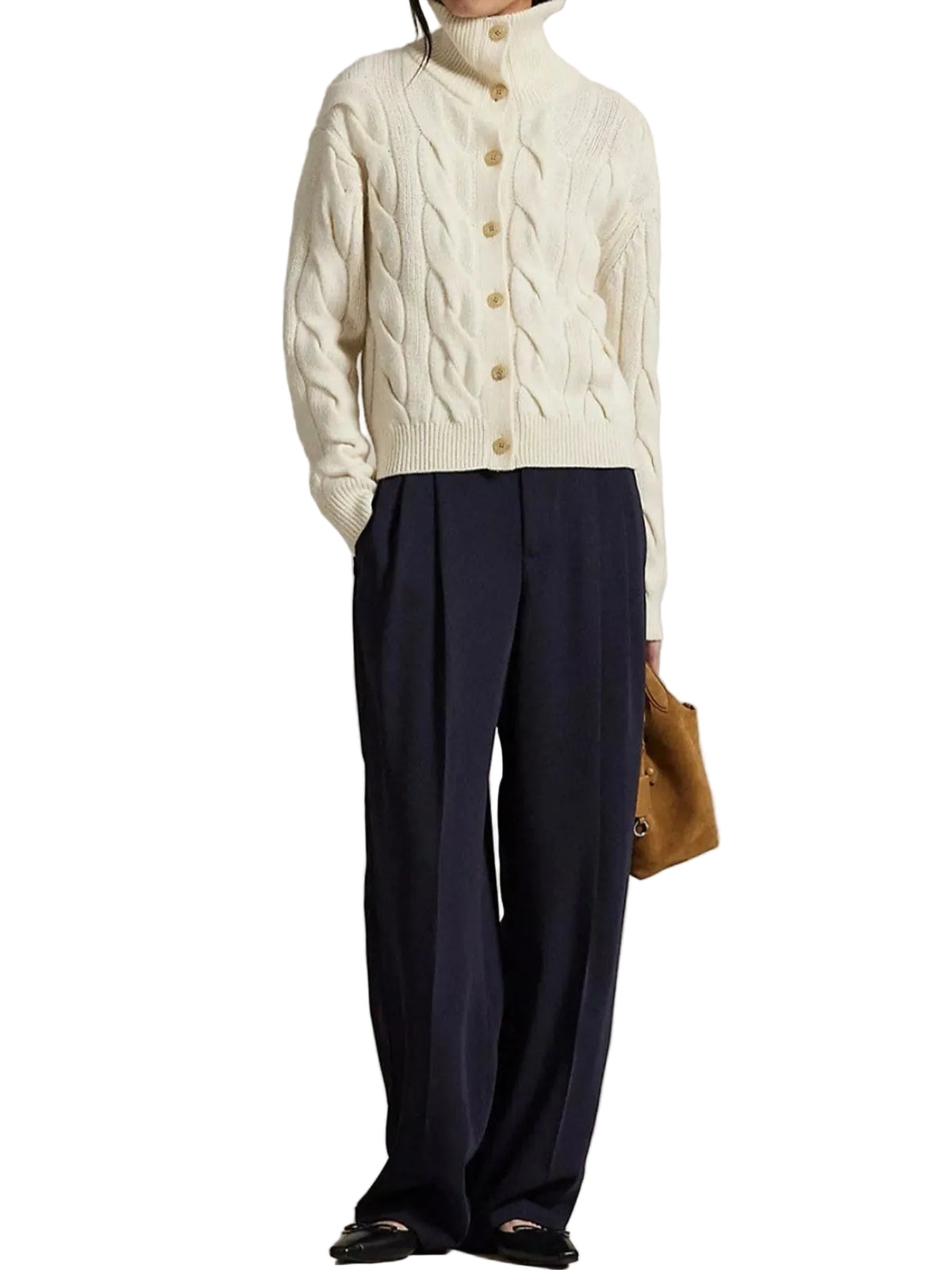 A model wearing a cream cable-knit mock-neck cardigan with gold buttons, navy blue wide-leg trousers, and black flat shoes, holding a brown leather bag against a textured beige studio backdrop.
