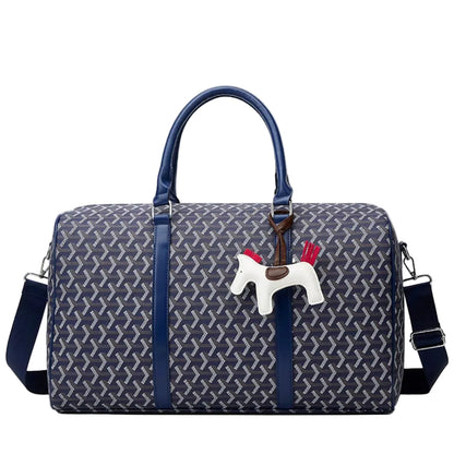 A navy blue Goyard duffel bag with a signature chevron pattern, featuring a white Swedish horse charm with red reins hanging from the zipper.