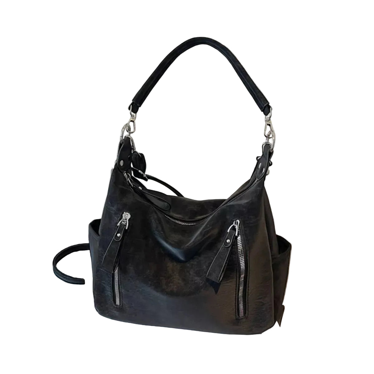 A black leather hobo shoulder bag with silver-tone hardware, displayed on a white book next to a black suitcase against a textured beige wall.