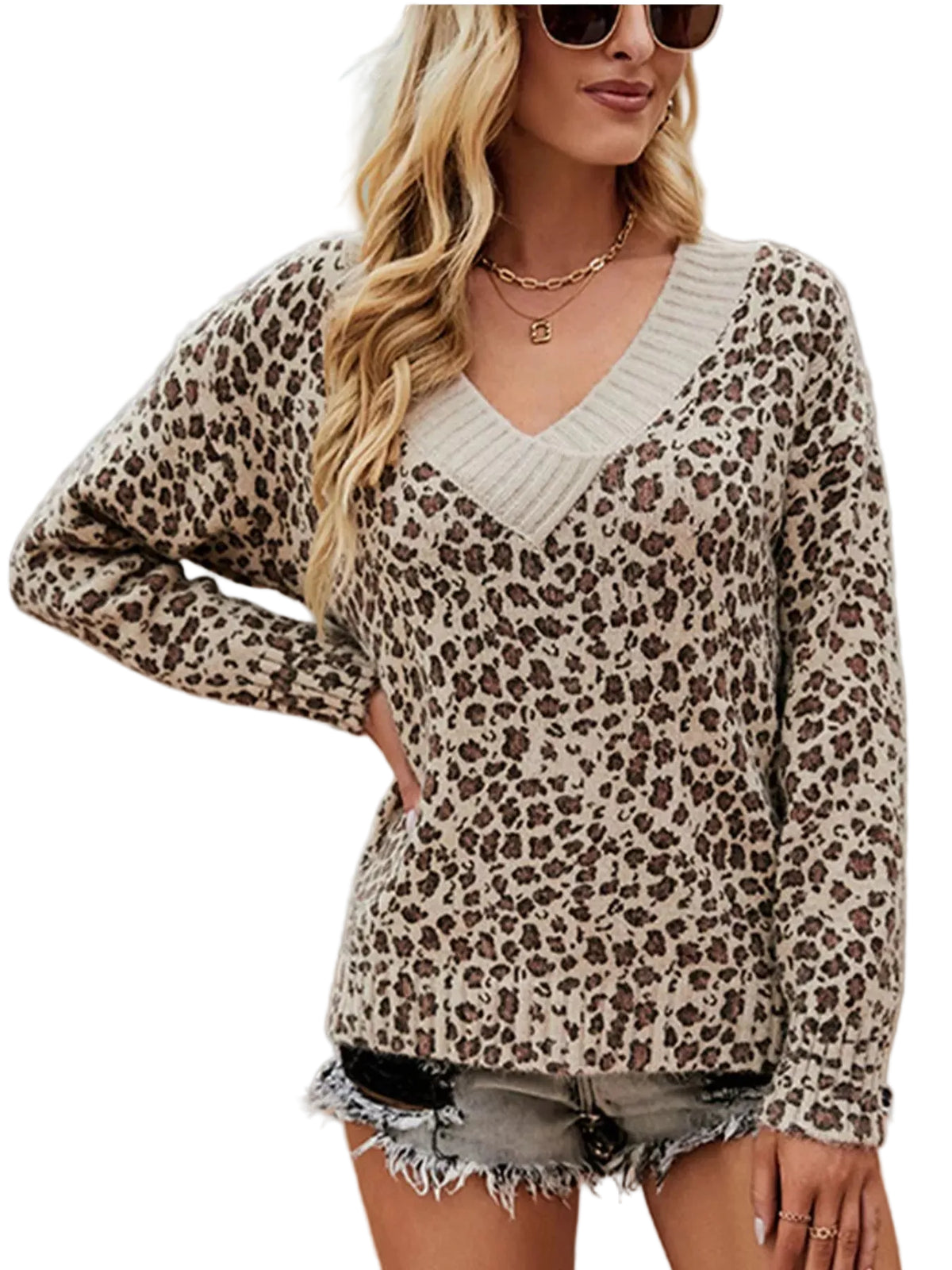 A woman wearing a beige and brown leopard print long-sleeve sweater with a cream ribbed V-neck trim, paired with frayed denim shorts, standing outdoors in front of a rustic blue door.