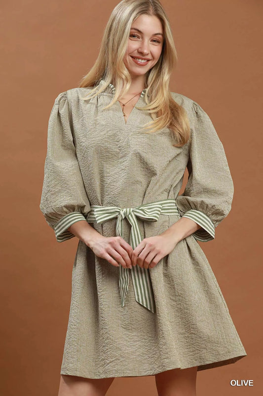 Woman wearing a beige dress with puff sleeves on a brown background