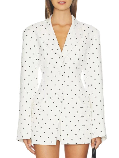 A model wearing a white long-sleeve blazer-style mini skirt with a black polka dot pattern, shown from the neck down against a plain white background.