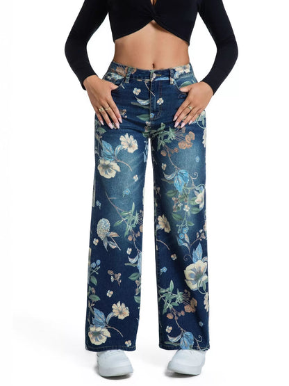 A model wearing a pair of dark blue wide-leg jeans with a light blue, beige, and white floral print, styled with a black long-sleeve crop top and white sneakers against a white background.