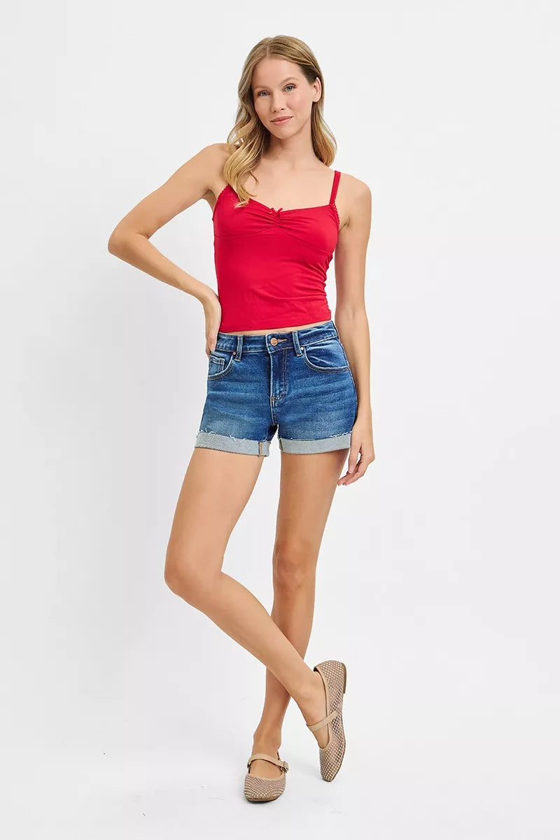 Woman wearing a red tank top and blue denim shorts on a white background