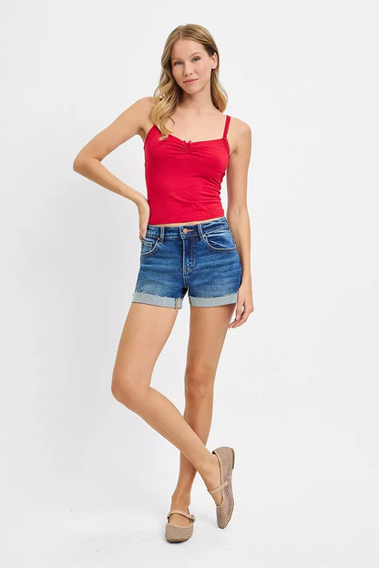Woman wearing a red tank top and blue denim shorts on a white background