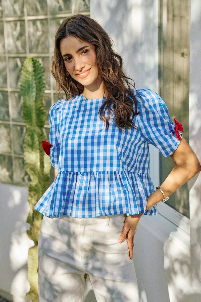 Woman wearing a blue checkered top with puffed sleeves in an outdoor setting.