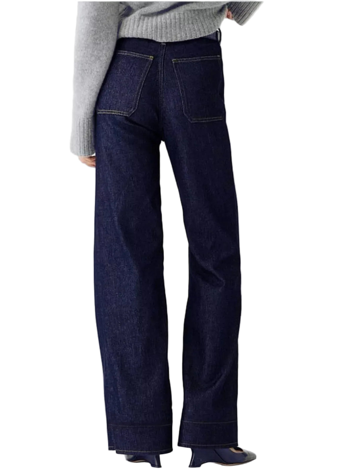 A person shown from the back wearing dark indigo wide-leg jeans, a gray knit sweater, and dark flat shoes against a plain white studio background.