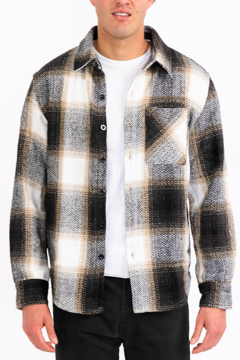 Person wearing a plaid shirt over a white t-shirt with a black background