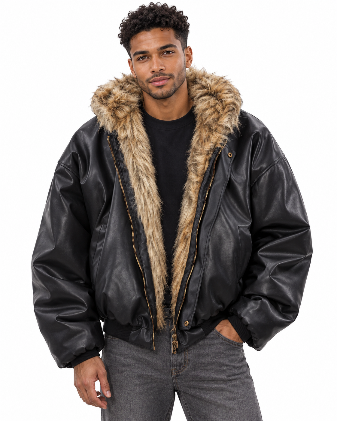 A man wearing a black faux-leather bomber jacket with a large tan and brown faux-fur collar, styled over a black t-shirt and gray jeans against a white background.