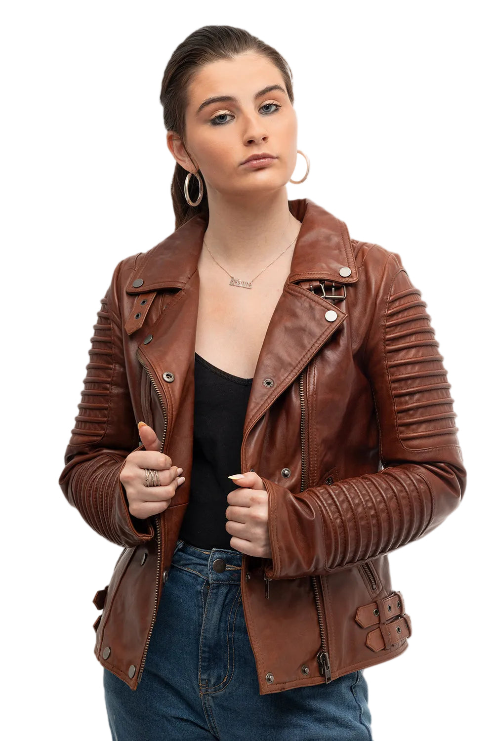 A woman wearing a brown leather moto jacket with ribbed sleeves and silver hardware, styled with a black top and blue jeans against a light gray background.