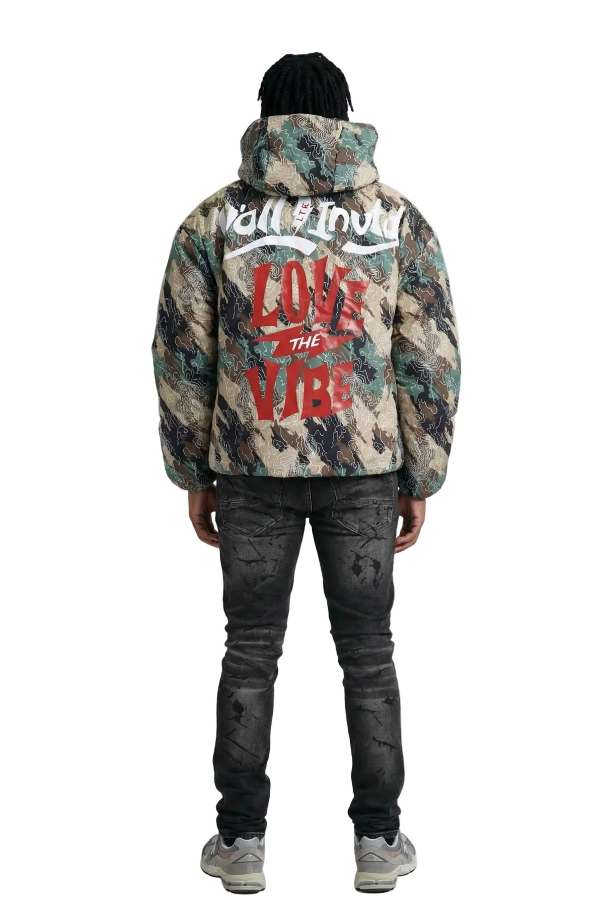 Person wearing a camouflage jacket with text on the back, standing against a white background
