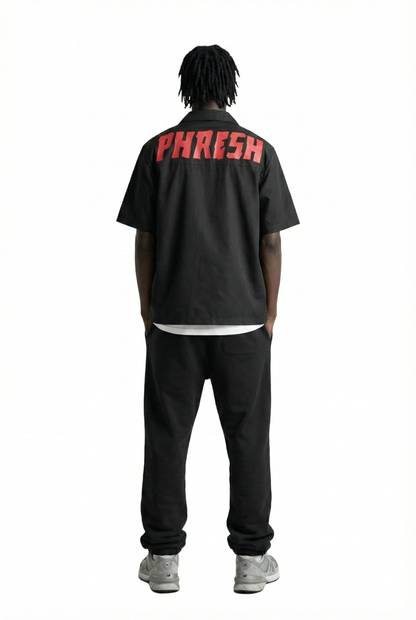 Person wearing a black shirt with 'PHRESH' text on the back, standing against a white background