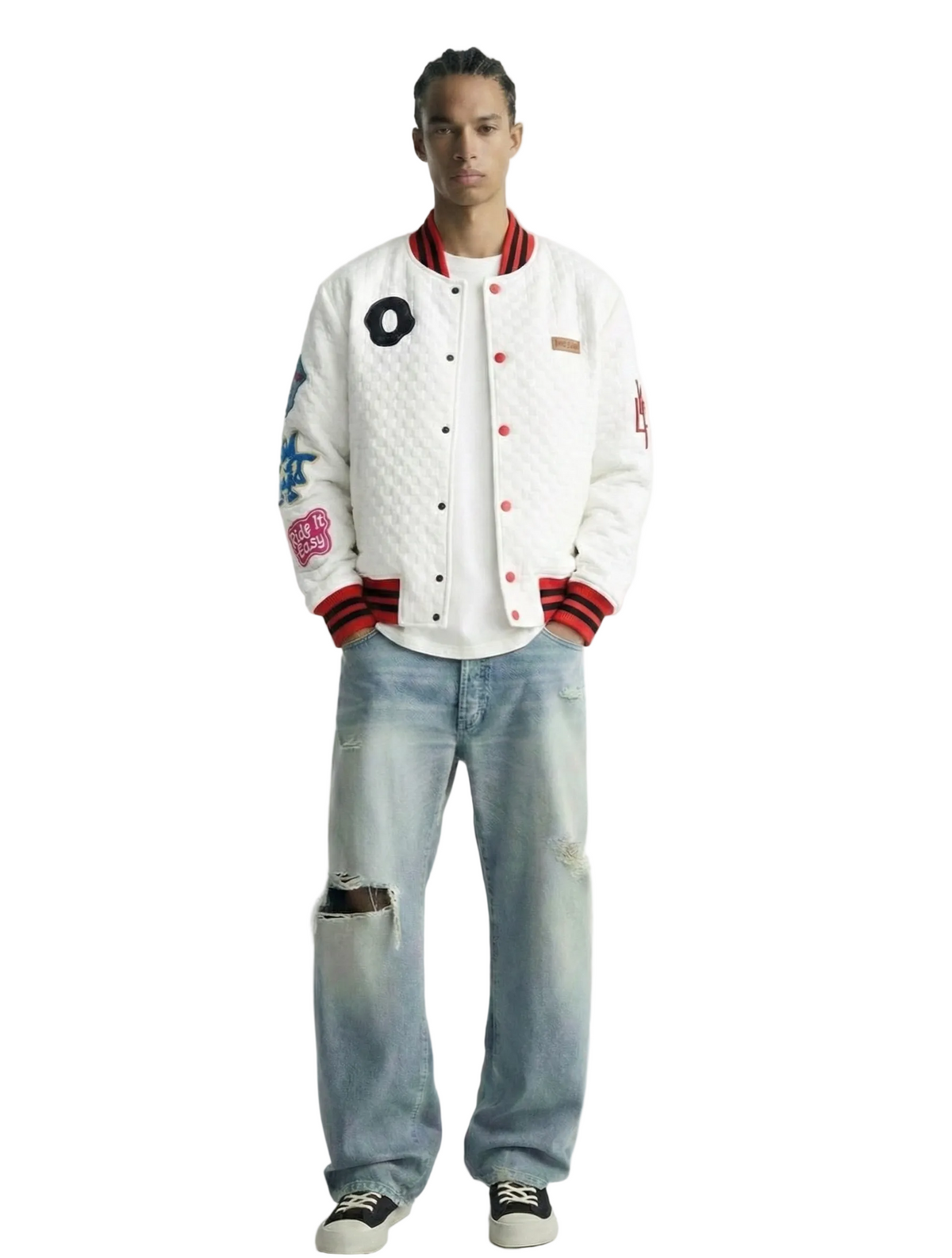 Person wearing a white varsity jacket with colorful designs and light blue jeans on a white background