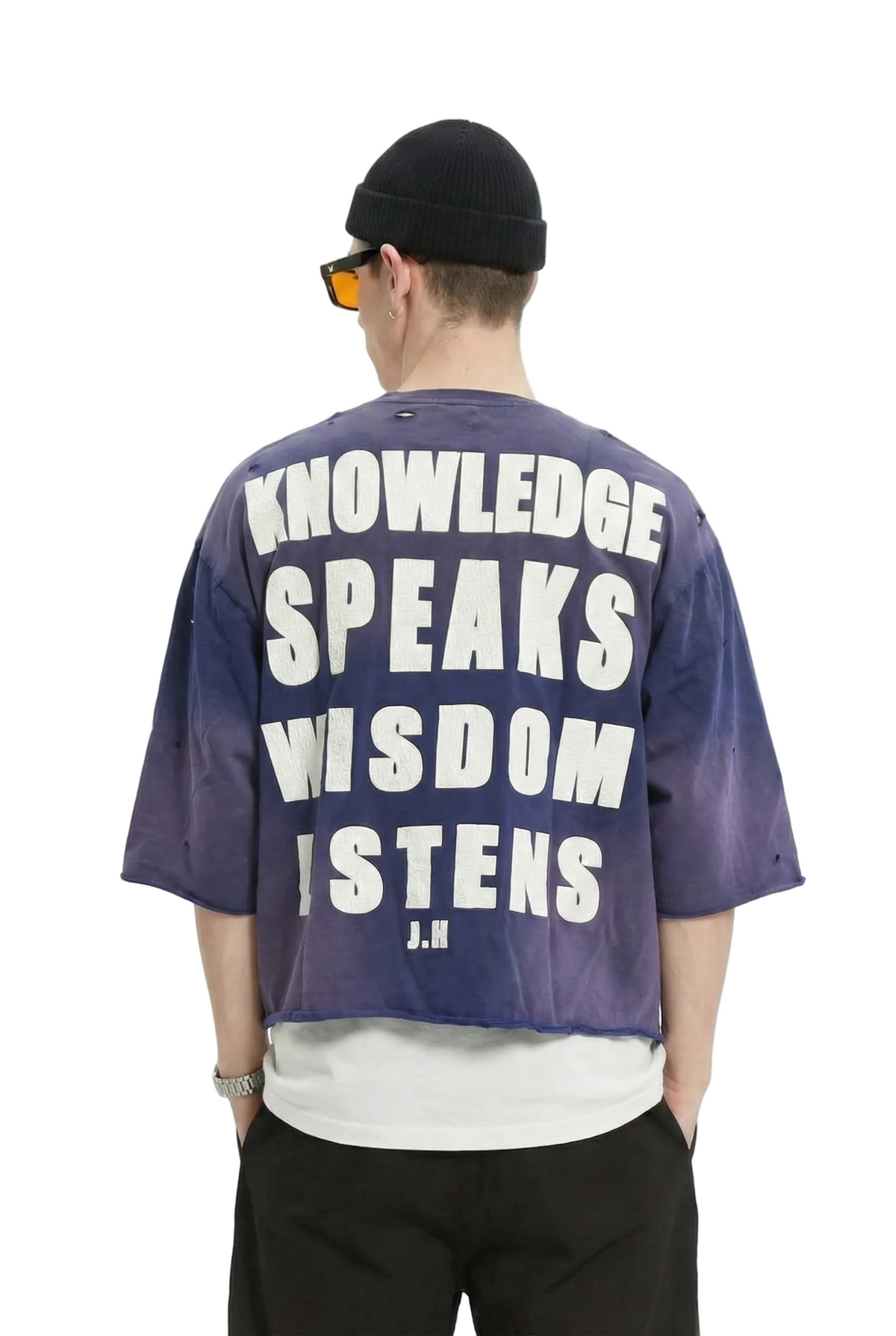 Person wearing a purple shirt with text on the back, standing against a white background