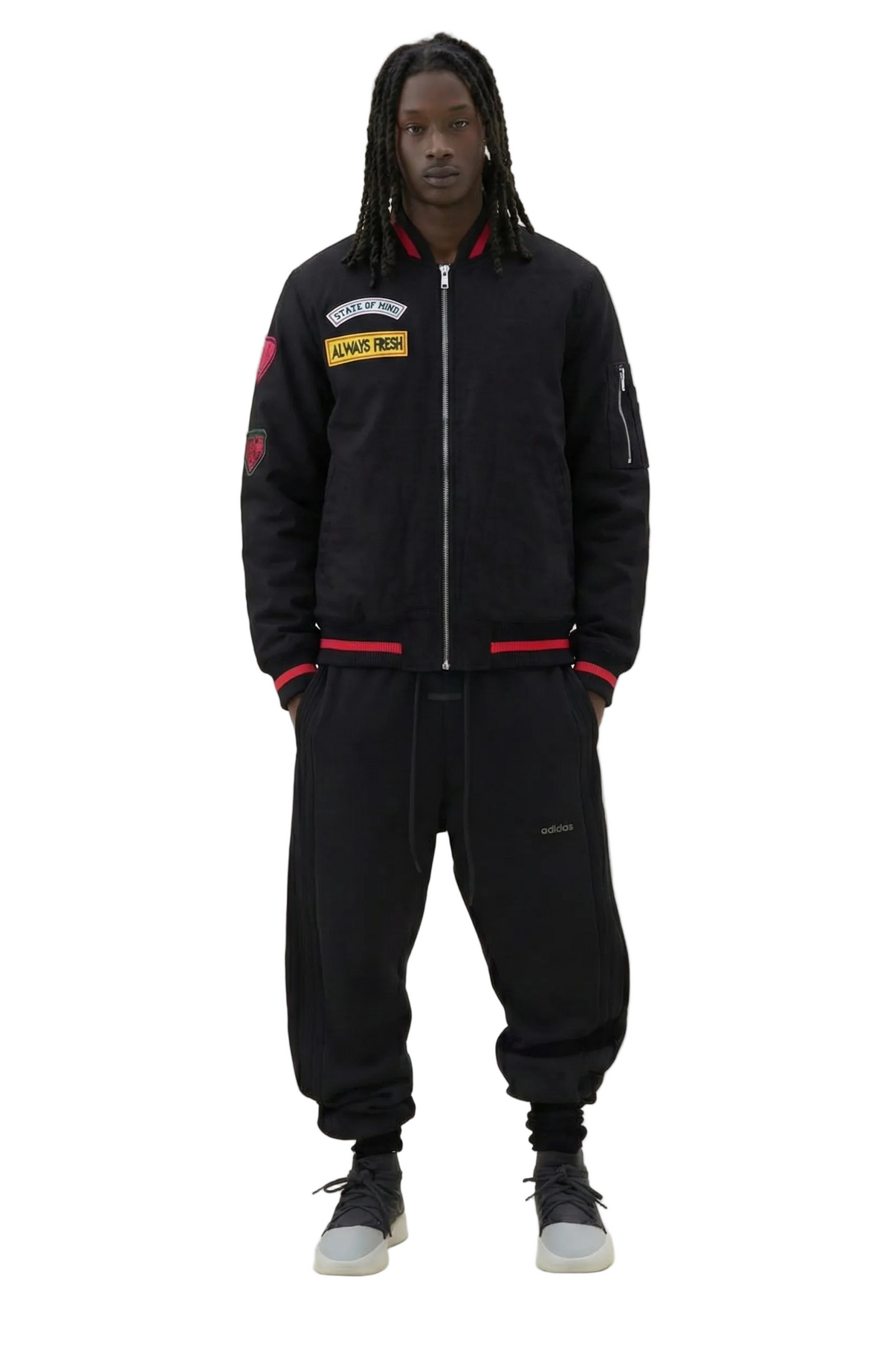 Person wearing a black tracksuit with various patches on a white background