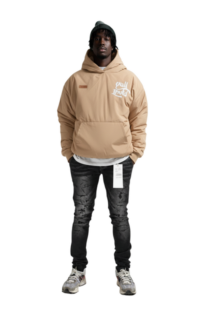 Person wearing a beige hoodie with text and dark jeans on a white background