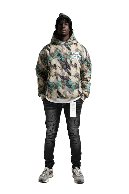 Person wearing a camouflage hoodie with branding on a white background