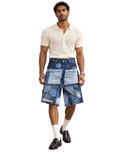 A man modeling a cream short-sleeve polo shirt and blue patchwork denim shorts against a plain white background.