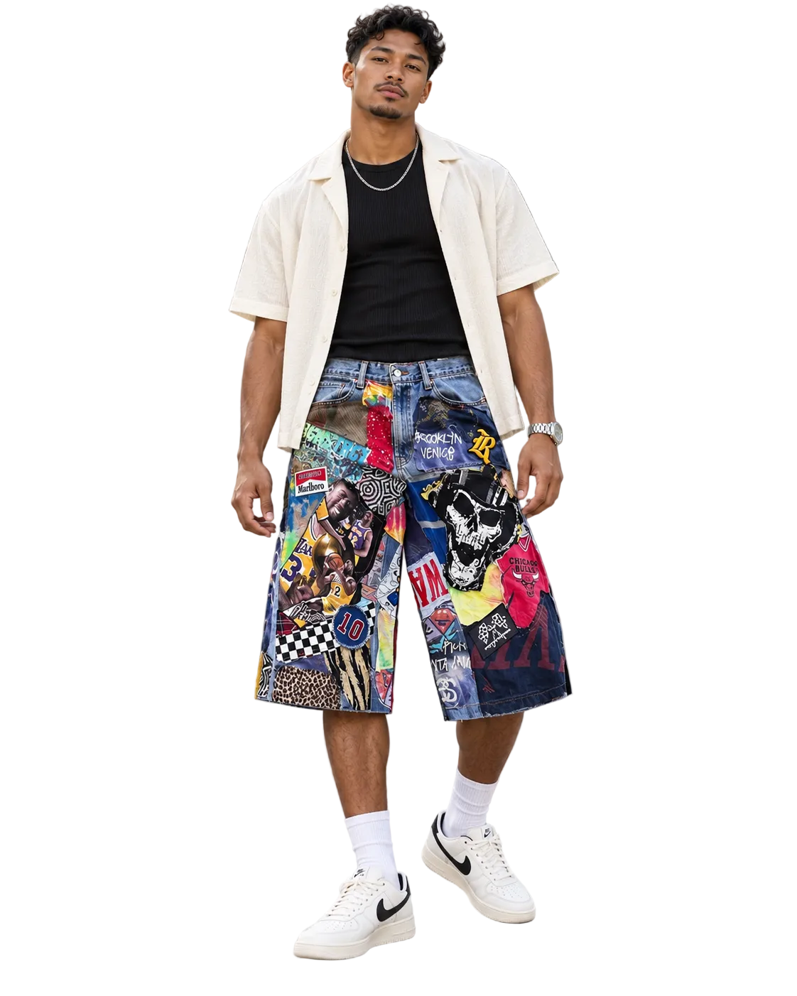 A man stands outdoors in front of a modern glass building, wearing a cream short-sleeve button-up shirt over a black t-shirt, and highly detailed multicolor patchwork denim shorts with graphic prints, white socks, and white Nike sneakers.
