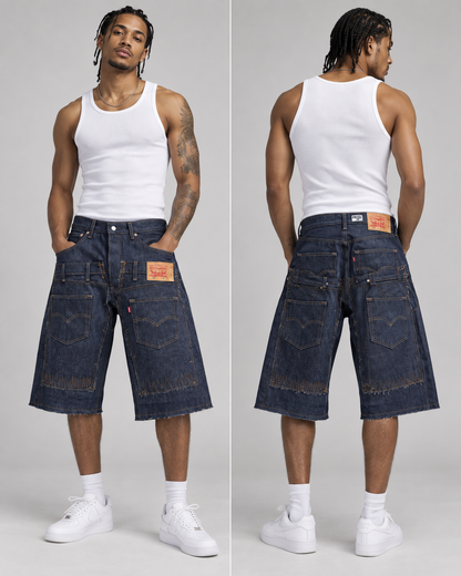 A model shown from the front and back wearing oversized dark blue denim shorts with a white tank top and white sneakers, against a light gray studio background.