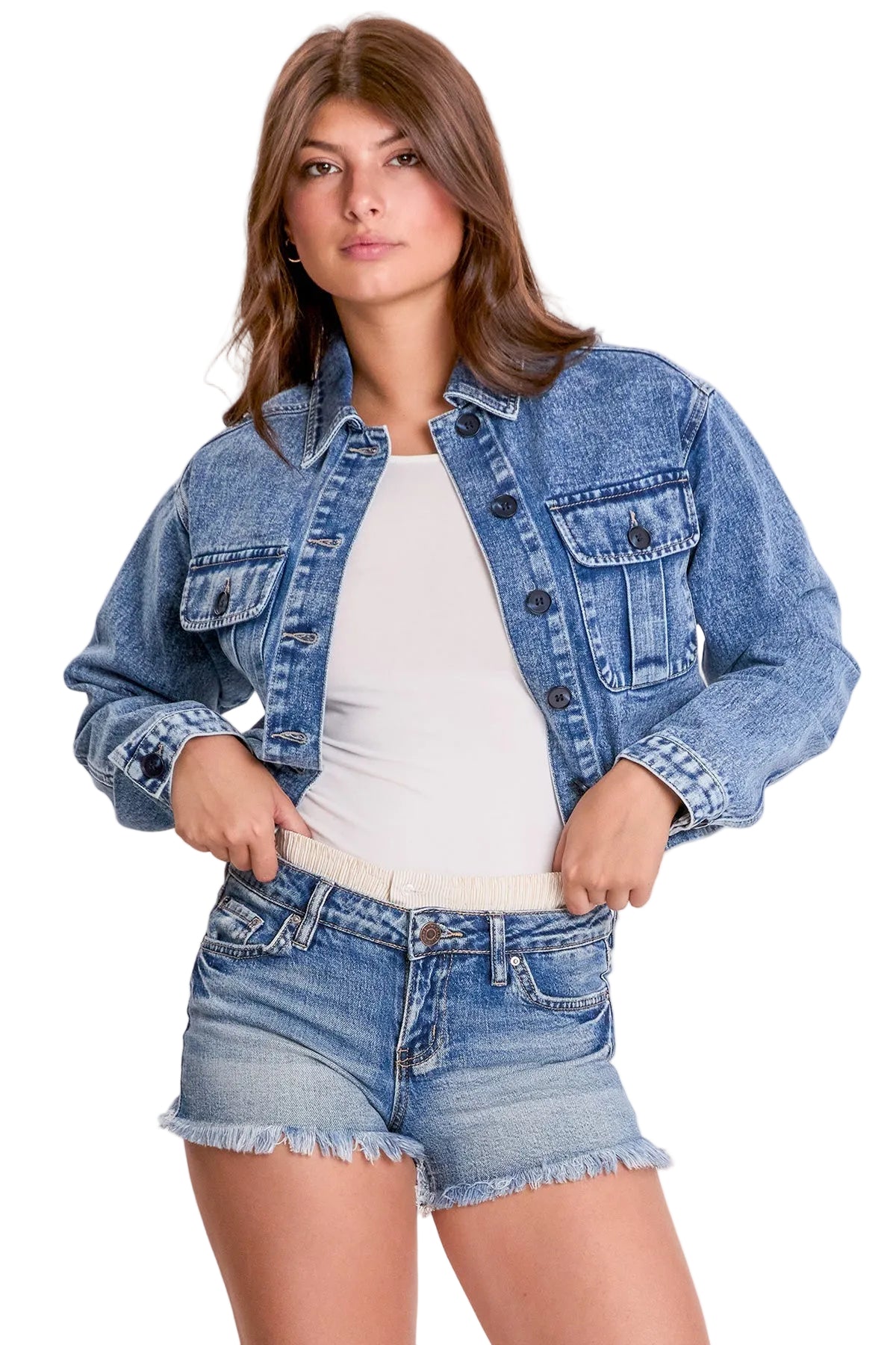 Woman wearing a denim jacket and shorts on a plain background