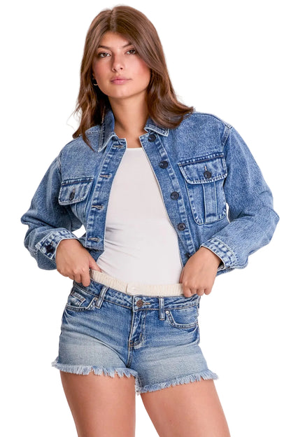 Woman wearing a denim jacket and shorts on a plain background