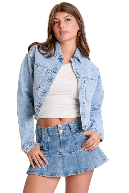 Woman wearing a denim jacket and skirt on a plain background