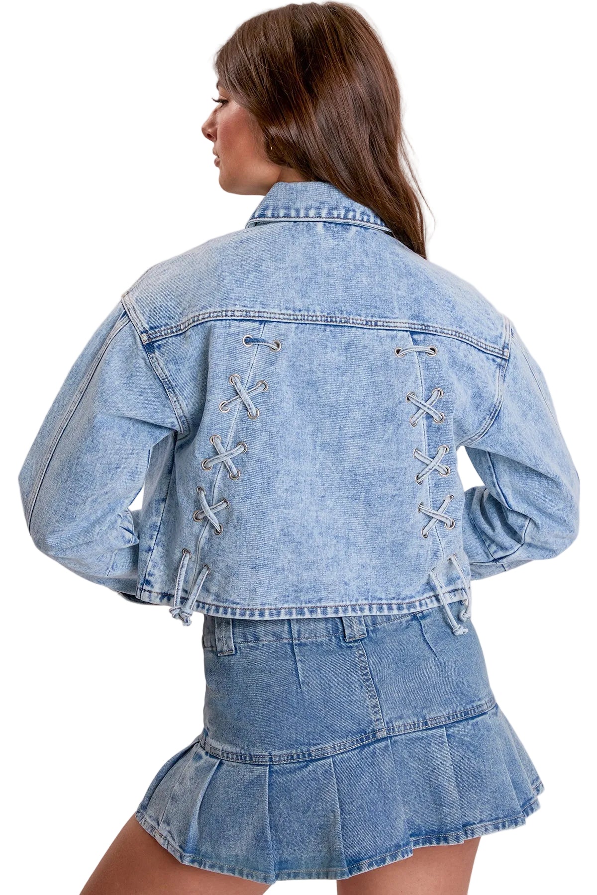 A model shown from the back wearing a light blue denim jacket and matching denim mini skirt. The jacket features decorative lace-up details on the back.