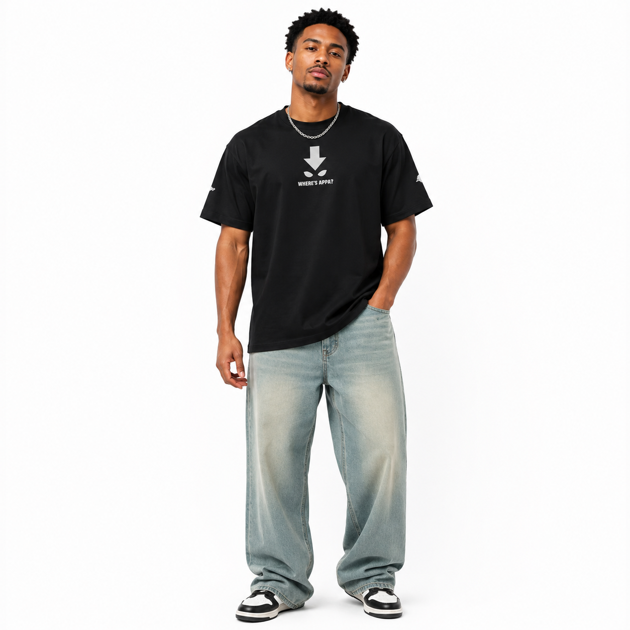 Man wearing a black t-shirt with a logo and light blue jeans on a white background