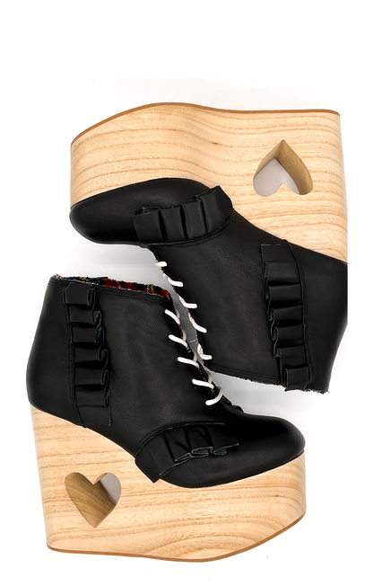 Black wedge boots with wooden soles on a white background