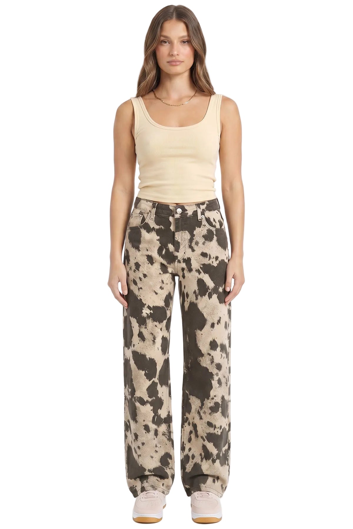 Woman wearing a beige tank top and patterned pants on a white background