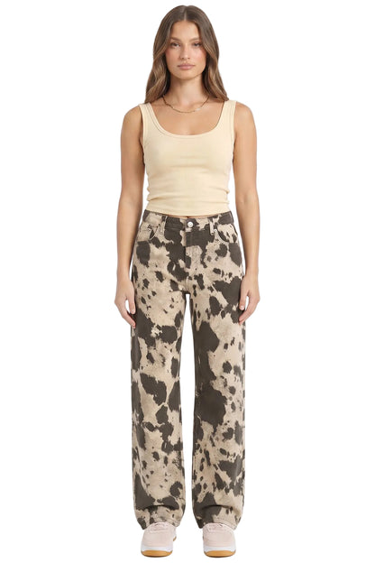 Woman wearing a beige tank top and patterned pants on a white background