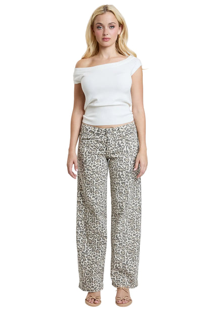 Woman wearing a white top and patterned pants on a plain background