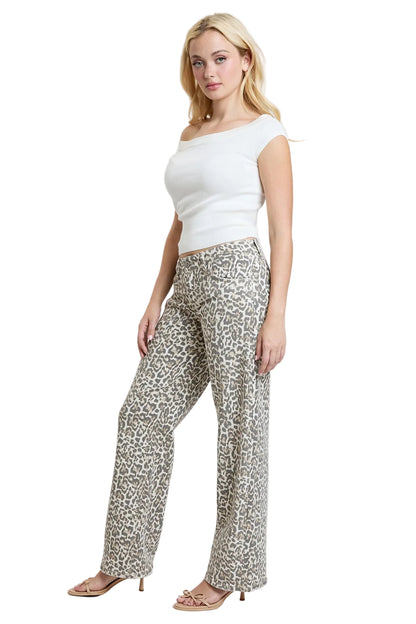 Woman wearing a white top and leopard print pants on a plain background