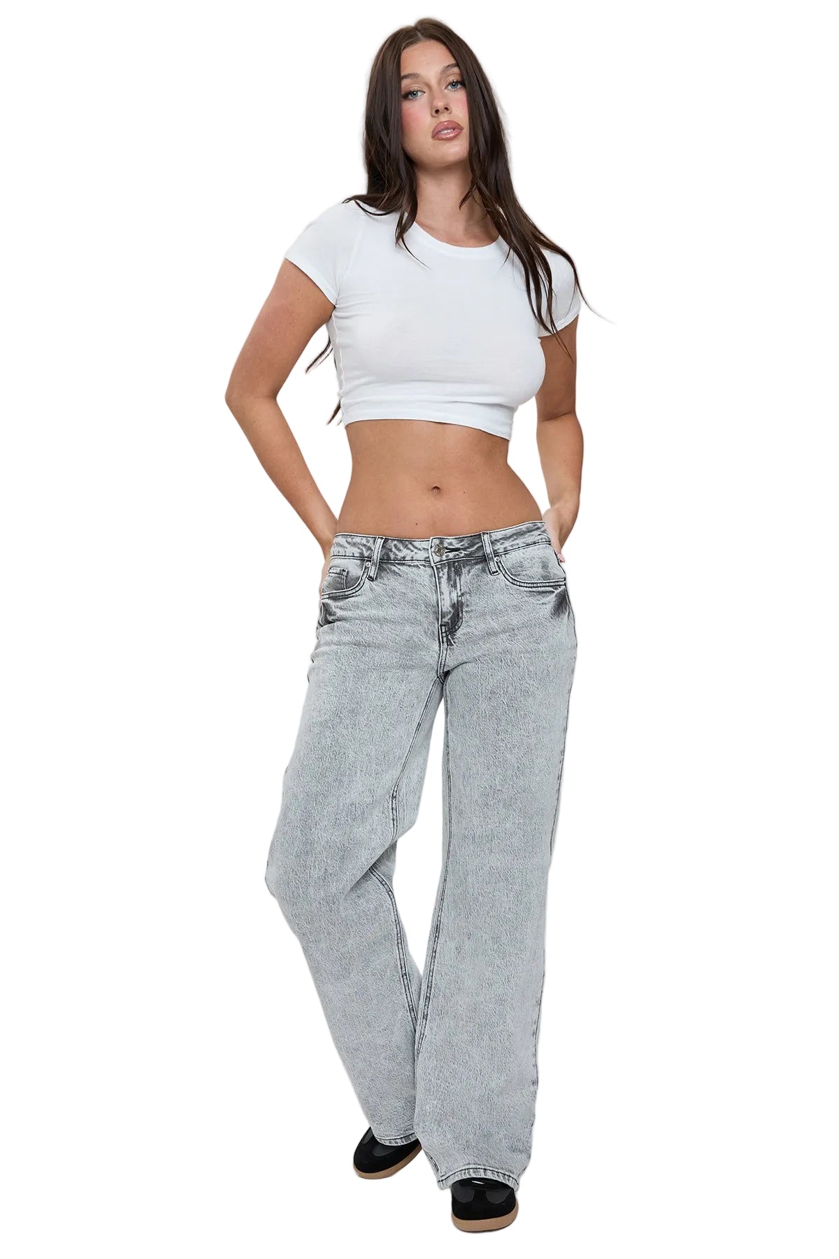 Woman wearing a white crop top and light blue jeans on a plain background