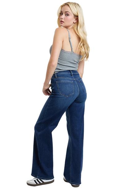 Woman wearing blue jeans and a gray tank top on a white background
