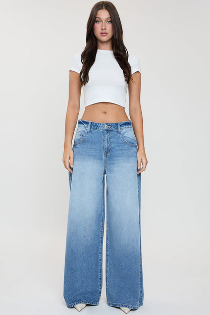 Woman wearing a white crop top and blue jeans on a plain background