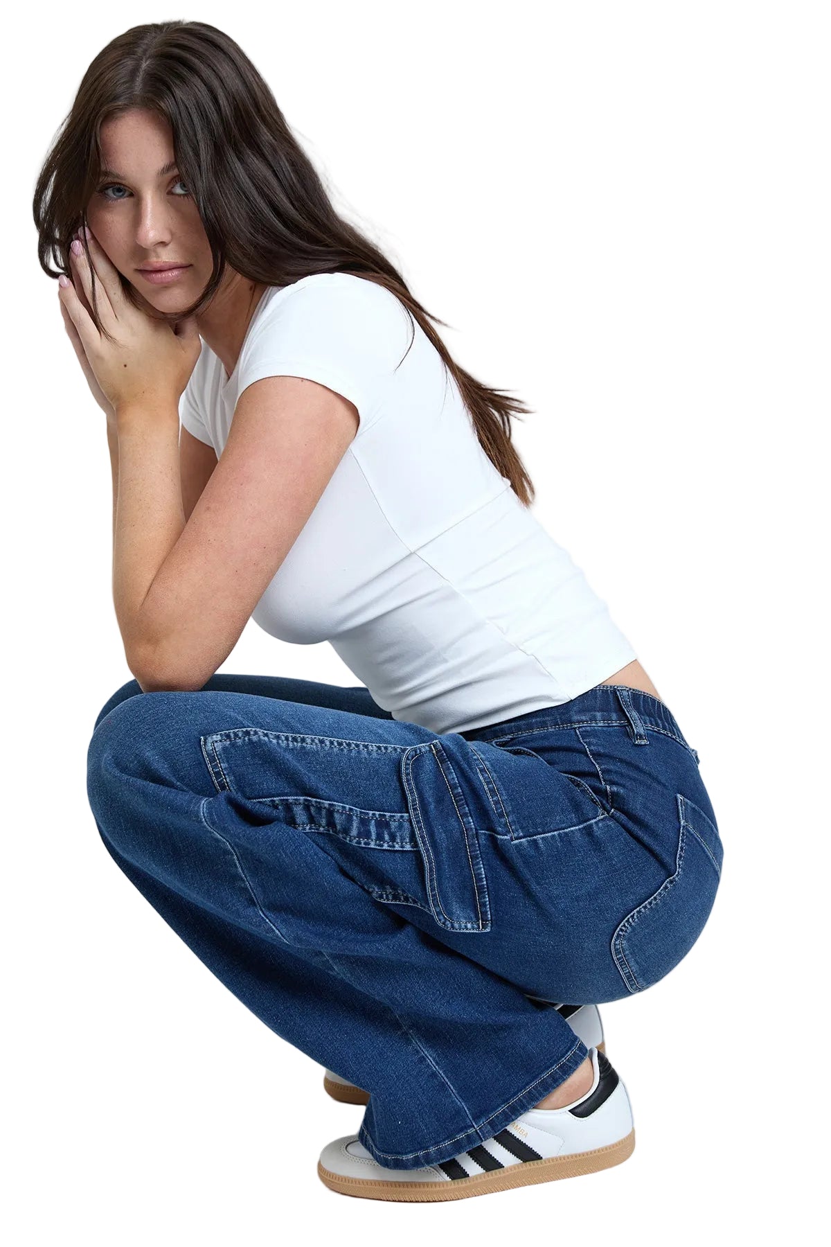 Woman wearing a white t-shirt and blue jeans, sitting on the floor with a white background