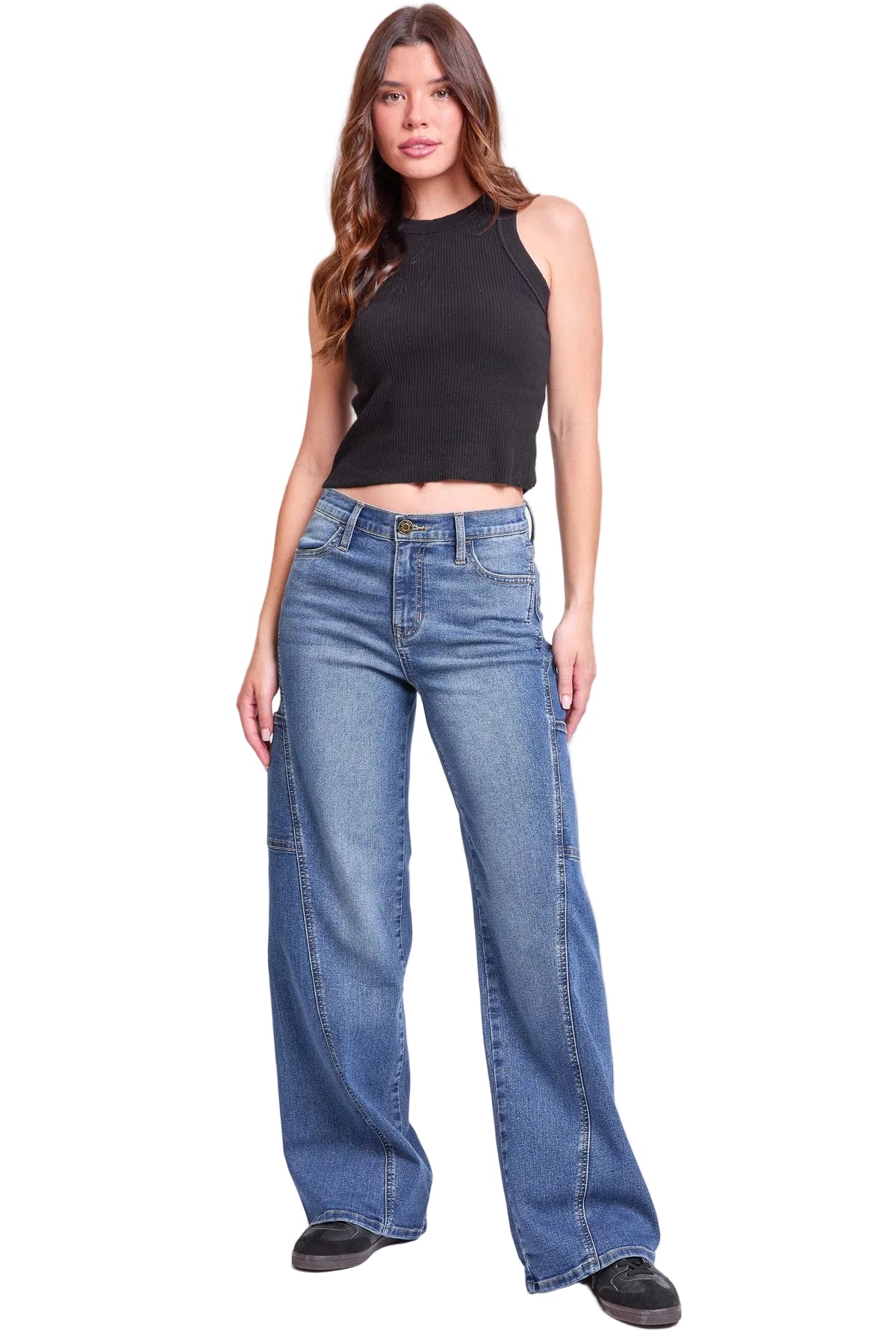 A woman modeling a black sleeveless crop top and wide-leg blue jeans against a plain light gray studio background.