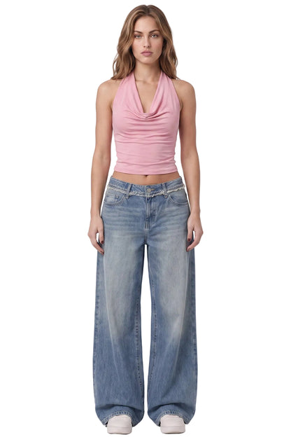 A woman modeling a light pink halter crop top and wide-leg light-wash blue jeans against a plain white studio background.